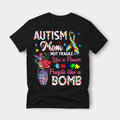 Black t-shirt printed with a watercolour autism mom design in pink and green — floral lettering, a grenade-shaped vase of roses, and a puzzle-piece autism awareness ribbon
