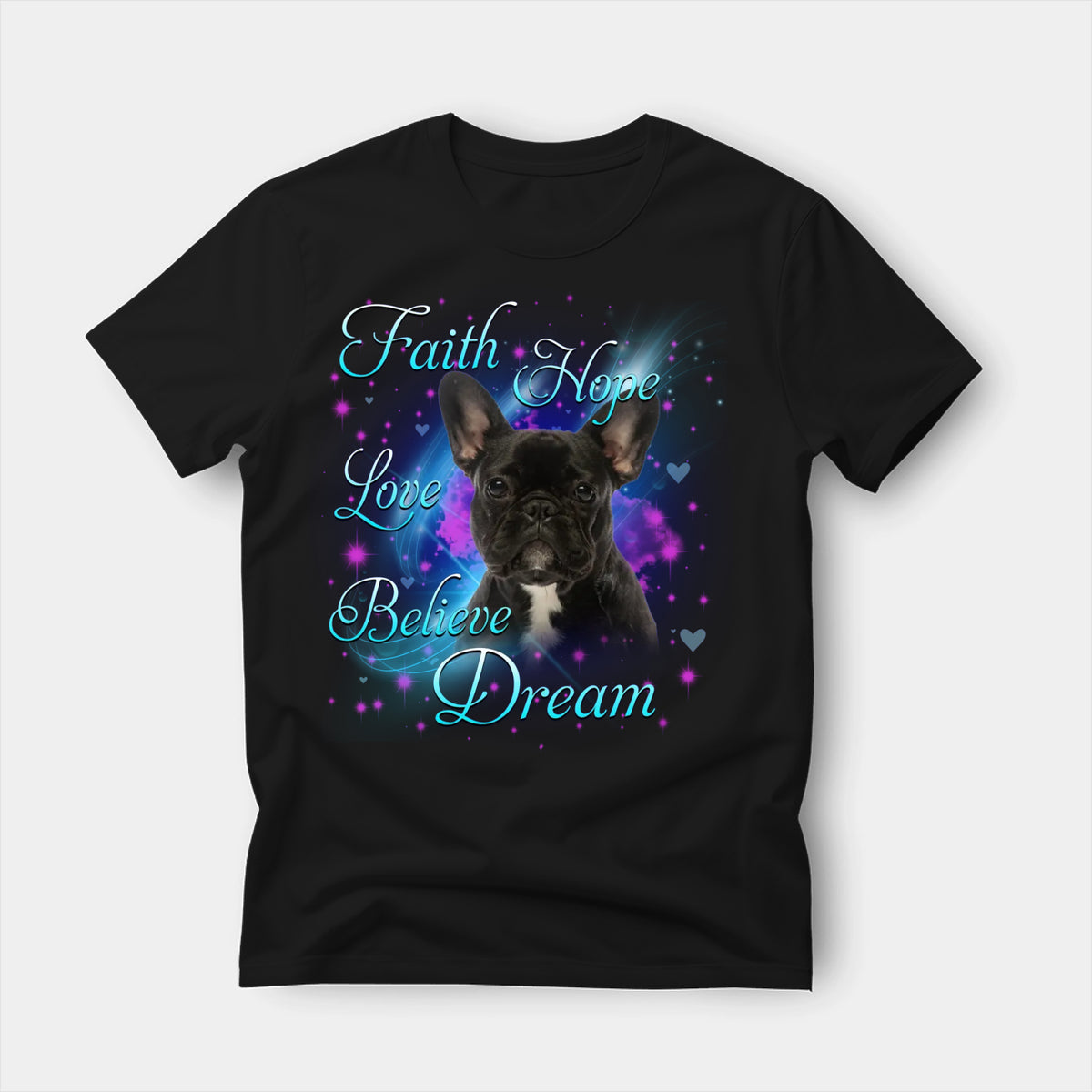 Black t-shirt printed with a French Bulldog with the words Faith, Hope, Love, Believe and Dream in glowing script on a sparkling blue background