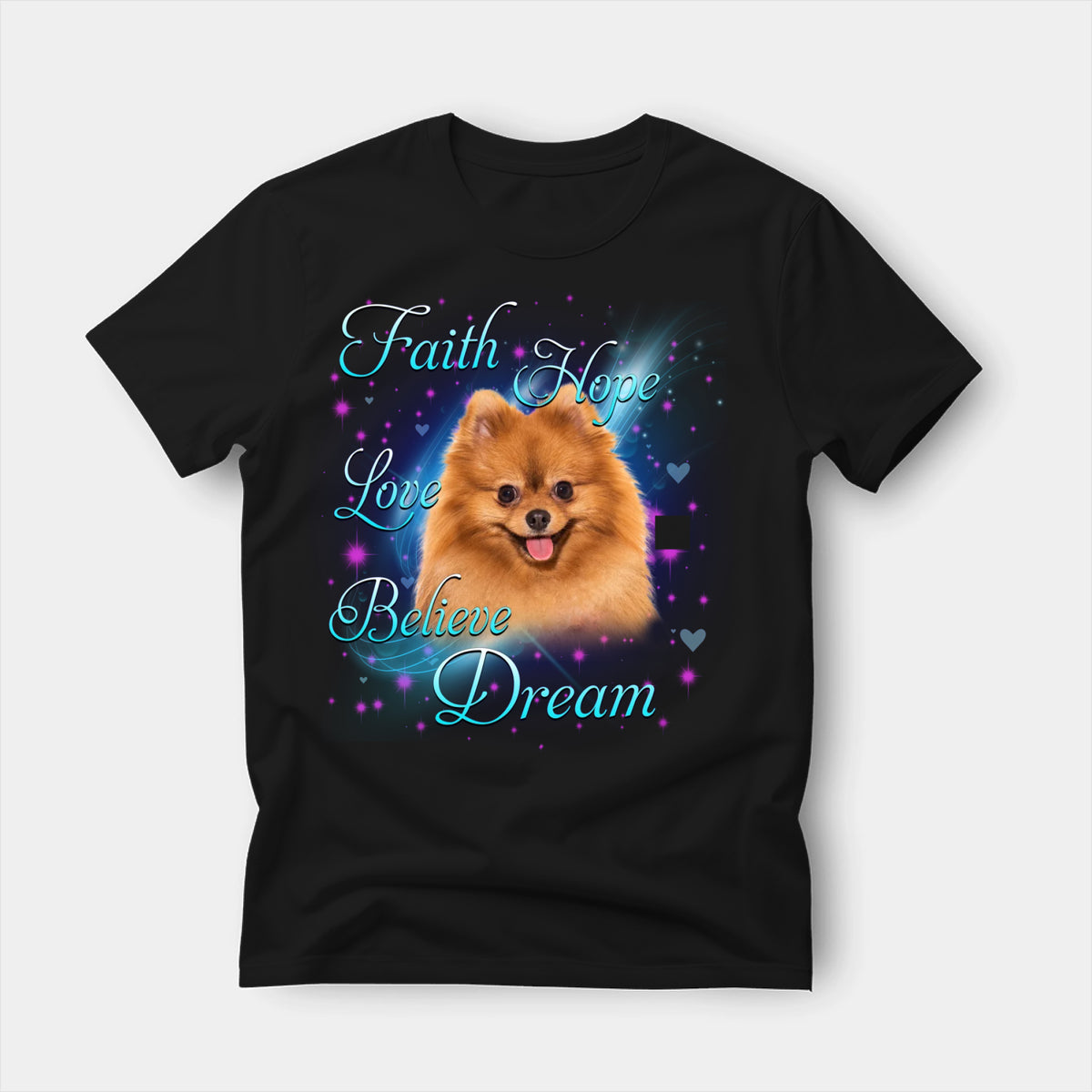 Black t-shirt printed with a Pomeranian with the words Faith, Hope, Love, Believe and Dream in glowing script on a sparkling blue background